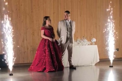 Un couple élégant se tient debout entre des fontaines d'étincelles dans une salle aux murs en bois.