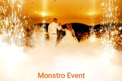 Un couple danse au milieu de fumée et d'étincelles dans une salle illuminée, entouré d'invités.