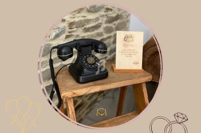 Téléphone rétro noir et livre d'or en bois sur une table, présentés comme éléments de décoration événementielle.