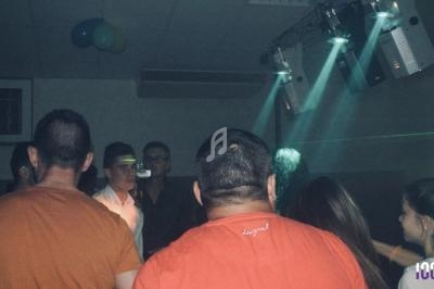 Des personnes dansent dans une salle sombre éclairée par des projecteurs et des lumières colorées.