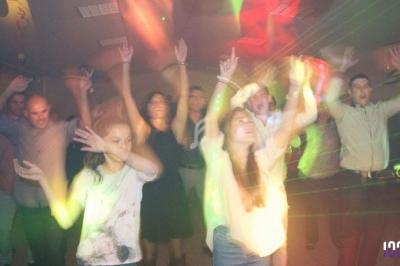 Des personnes dansent sous des lumières colorées dans une ambiance festive et animée.