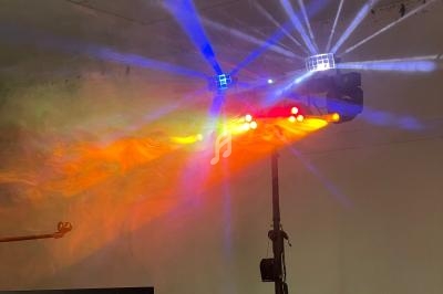 Effets lumineux colorés projetés par un équipement d'éclairage sur pied dans une pièce sombre.