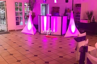 Salle de réception avec piste de danse, éclairage violet, table décorée et équipement de sonorisation installé.