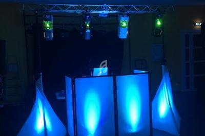 Installation de DJ avec éclairage LED bleu, comprenant une table de mixage et des structures lumineuses triangulaires.