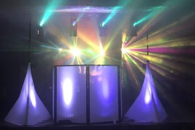 Jeu de lumières colorées projetées sur une scène avec deux structures blanches et un écran central.