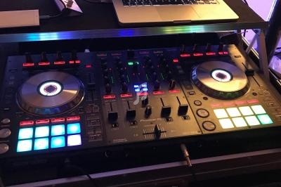 Table de mixage DJ avec platines lumineuses et ordinateur portable affichant un logiciel de mixage.