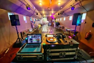 Poste de DJ avec platines, ordinateur portable et casque dans une salle colorée et éclairée pour un événement.