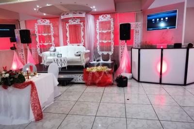 Salle de réception décorée en rouge et blanc avec une estrade, un canapé, une table d'honneur et un espace DJ.