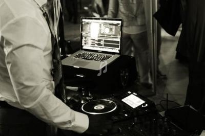 Un DJ mixant de la musique sur une table de mixage avec un ordinateur portable lors d'un événement en soirée.
