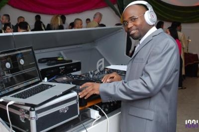 Un DJ en costume mixe de la musique sur une console avec un ordinateur portable lors d'un événement festif.