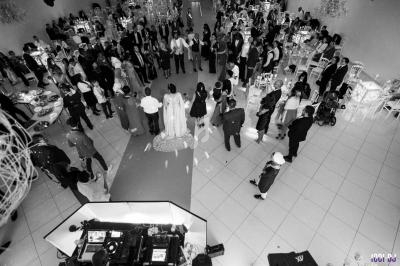 Vue aérienne en noir et blanc d'une salle de réception avec des invités rassemblés autour d'un couple au centre.