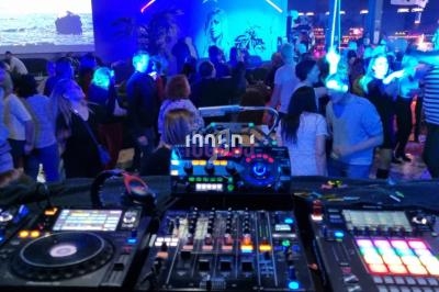 Vue depuis une table de mixage sur une piste de danse animée avec éclairages colorés et ambiance festive.