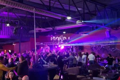 Salle animée avec des groupes de personnes discutant et dansant sous des lumières colorées dans une ambiance festive.