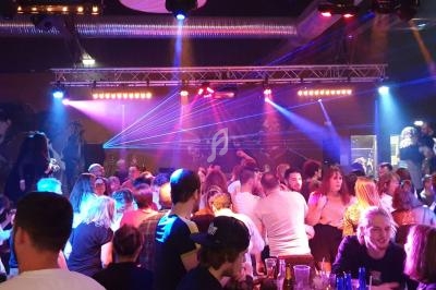 Foule de personnes dans une discothèque animée avec éclairages colorés et lasers.