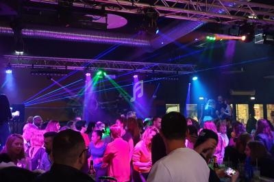 Groupe de personnes dans une salle sombre avec des jeux de lumières colorées et des lasers.