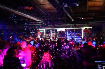 Foule dans un bar animé avec des lumières colorées et des bulles flottant dans l'air.