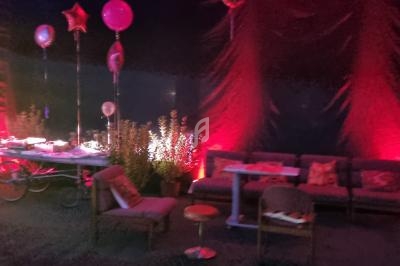 Espace lounge décoré avec des ballons, des canapés et un éclairage rouge dans une ambiance festive.