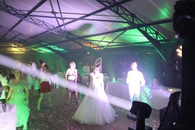 Des personnes dansent sous des jeux de lumière colorés dans une salle avec une structure métallique apparente.