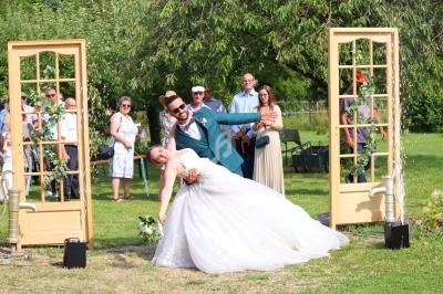 Un couple de mariés danse en extérieur devant des invités, entouré de décorations champêtres.