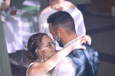 Un couple danse tendrement lors d'un événement, éclairé par une lumière douce dans une salle décorée.