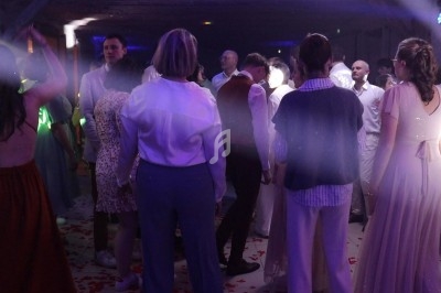Groupe de personnes dansant dans une salle éclairée par des lumières colorées, avec des pétales au sol.