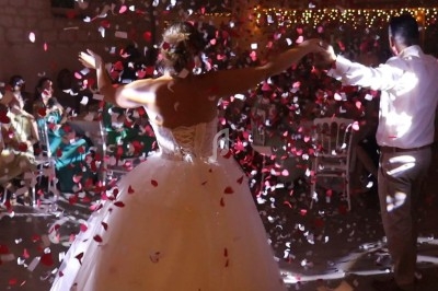 Un couple danse sous une pluie de confettis rouges et blancs lors d'une fête en soirée.