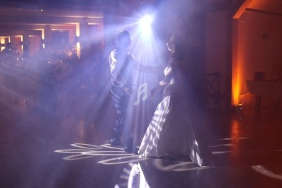 Un couple danse sous des lumières tamisées et des effets de fumée dans une salle de réception.