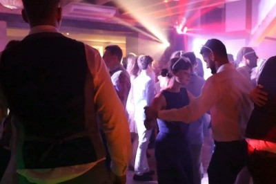 Personnes dansant dans une salle éclairée par des lumières colorées lors d'une fête ou d'un événement.