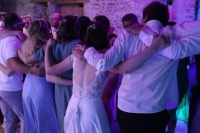 Groupe de personnes en tenue de soirée, bras dessus bras dessous, dans une ambiance éclairée par des lumières violettes.