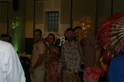 Des personnes déguisées posent ensemble dans une salle décorée pour une fête, avec des ballons en arrière-plan.