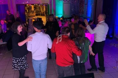 Des personnes dansent en groupe sur une piste éclairée par des lumières colorées, vue depuis une régie musicale.