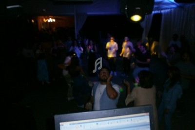 Groupe de personnes dansant sous des lumières tamisées lors d'une soirée, vu depuis une table de mixage.