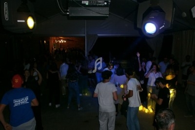 Des personnes dansent et discutent dans un espace sombre éclairé par des projecteurs colorés.