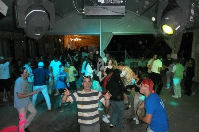 Groupe de personnes dansant sous un chapiteau éclairé, ambiance festive avec lumières colorées.