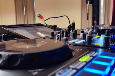 Table de mixage avec platine et boutons lumineux, installée dans une salle avec rideaux et ballons en arrière-plan.