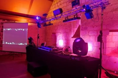 Installation de matériel de sonorisation et d'éclairage dans une salle en pierre, avec un écran de projection allumé.