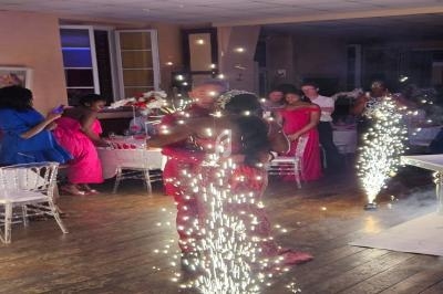 Des invités en tenue de soirée dansent au milieu de jets d'étincelles dans une salle décorée pour un événement.