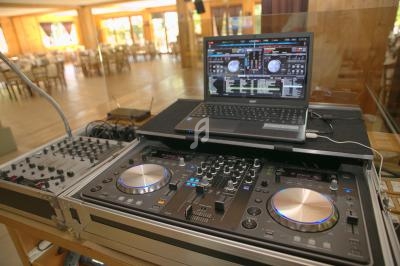 Poste de DJ avec une console de mixage, un ordinateur portable et des équipements audio dans une salle lumineuse.
