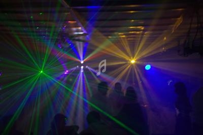 Jeux de lumières colorées avec des faisceaux laser dans une ambiance sombre, silhouettes de personnes en arrière-plan.