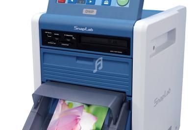 Imprimante photo compacte avec écran tactile affichant des images miniatures et une photo en cours d'impression.