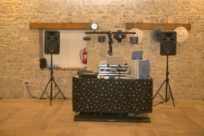 Matériel de sonorisation et éclairage installé devant un mur en pierre dans une salle.