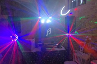 Jeux de lumières colorées projetés dans une salle avec des enceintes et des équipements de sonorisation.