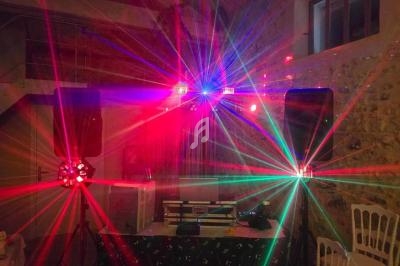 Effets lumineux colorés projetés dans une salle en pierre avec équipement de sonorisation et chaises blanches.