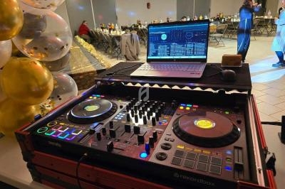 Table de mixage avec platines et ordinateur portable dans une salle de réception décorée de ballons dorés.