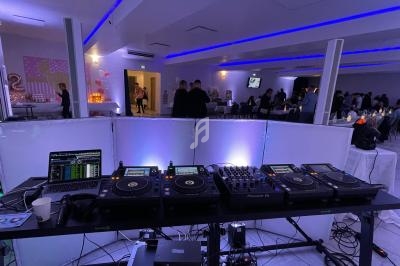 Équipement de DJ avec platines et ordinateur dans une salle éclairée de lumières bleues, lors d'un événement festif.