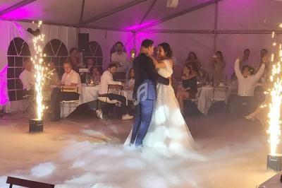 Un couple danse sous des étincelles et une lumière tamisée lors d'une réception sous chapiteau.