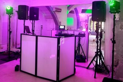 Installation de matériel de sonorisation et éclairage avec une table de mixage dans une salle à l'ambiance lumineuse rose.