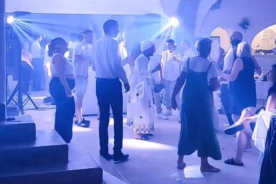Des personnes dansent dans une salle éclairée par des lumières bleues, créant une ambiance festive.