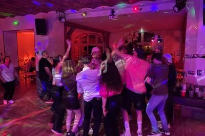Groupe de personnes dansant dans une salle éclairée par des lumières colorées lors d'une fête.