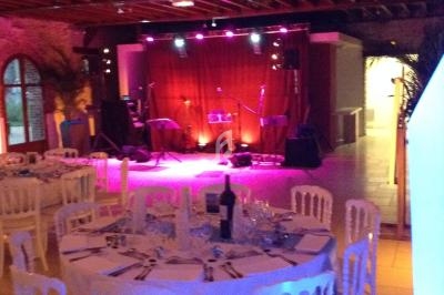 Salle de réception avec tables dressées et scène éclairée en arrière-plan pour une prestation musicale.